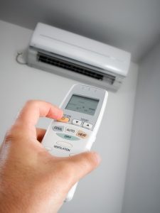 person-setting-the-thermostat-of-an-air-handler-with-a-remote